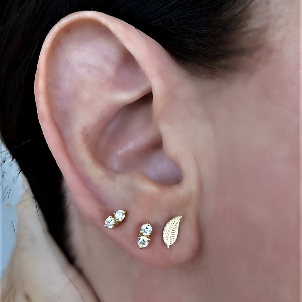 9kt rose gold leaf earring with complimentary earrings stacked on models ear 